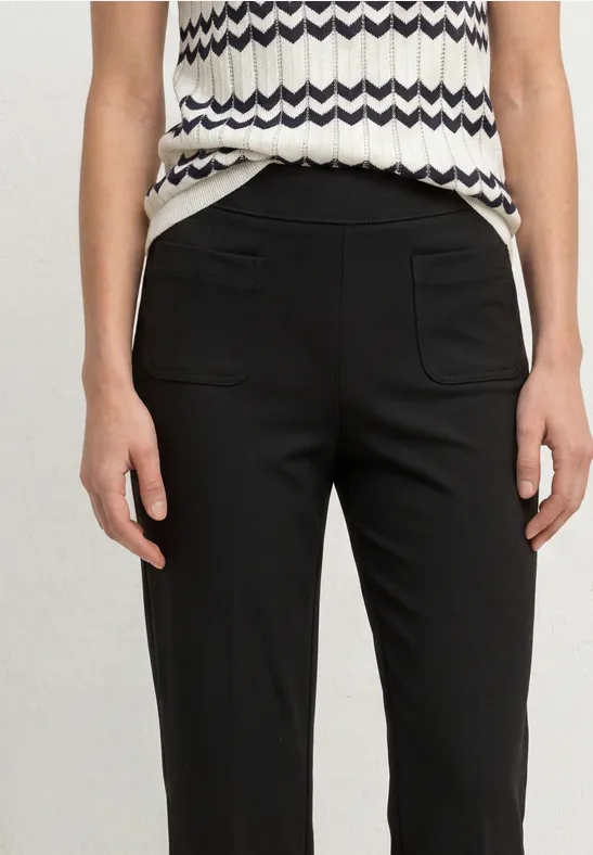 Schwarz-hose in schmaler Passform mit aufgesetzten Taschen kombiniert mit einem ärmellosen, gemusterten Top.