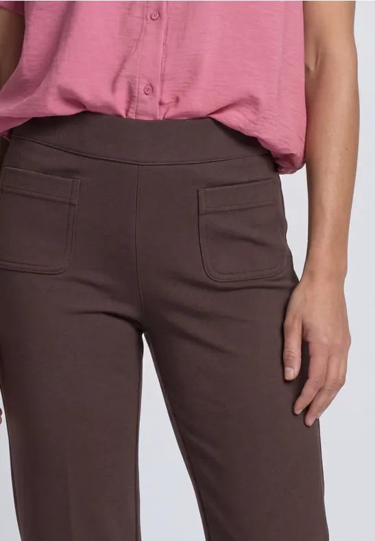 Frau trägt braune Hose mit aufgesetzten Taschen und eine rosa Bluse.