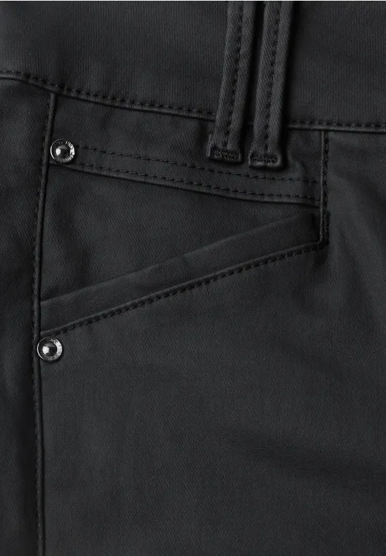 Gros plan sur un pantalon noir, poche en biais ornée de rivets