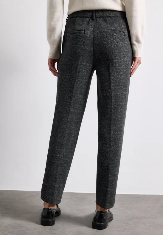 Eine Person trägt dunkelgraue, karierte Stoffhose im geraden Schnitt und schwarze Loafer.