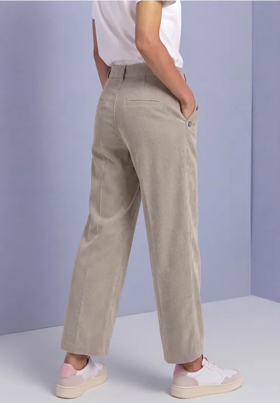 Beige Hose mit geradem Schnitt von der Seite getragen, kombiniert mit weißen Sneakern.