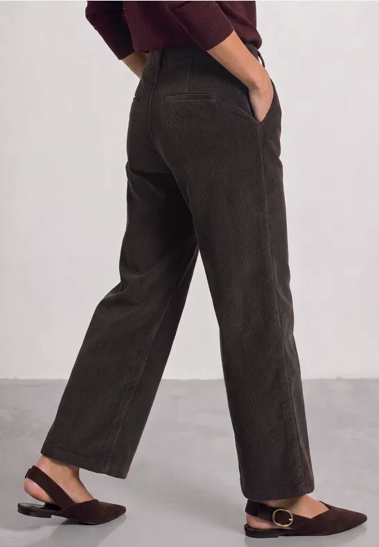 Dunkelbraune Cordhose mit weitem Schnitt und seitlichen Eingrifftaschen, kombiniert mit braunen Slippern.