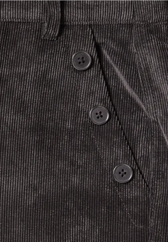 Detailaufnahme einer grauen Cordhose mit drei Knöpfen neben der Tasche.