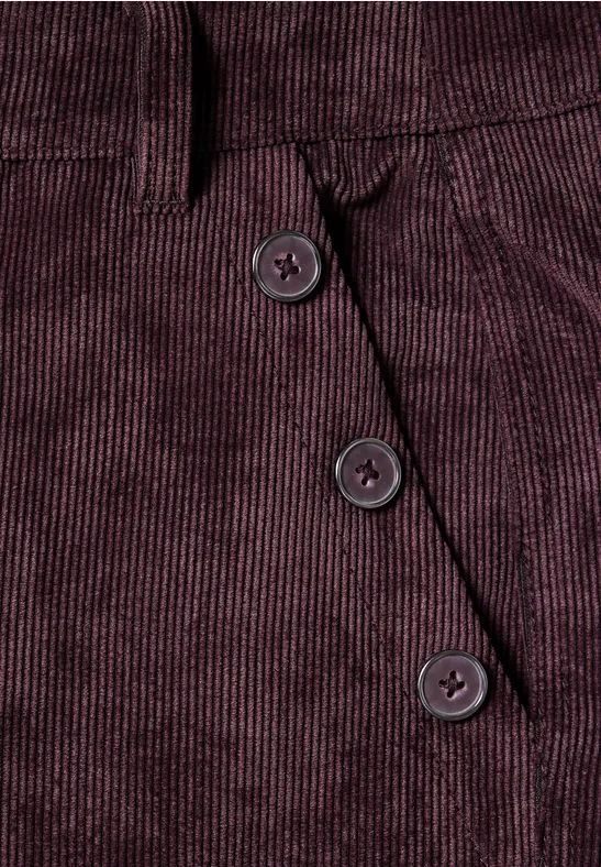 Bordeauxfarbener Cordstoff mit drei diagonalen Knöpfen neben einer Tasche