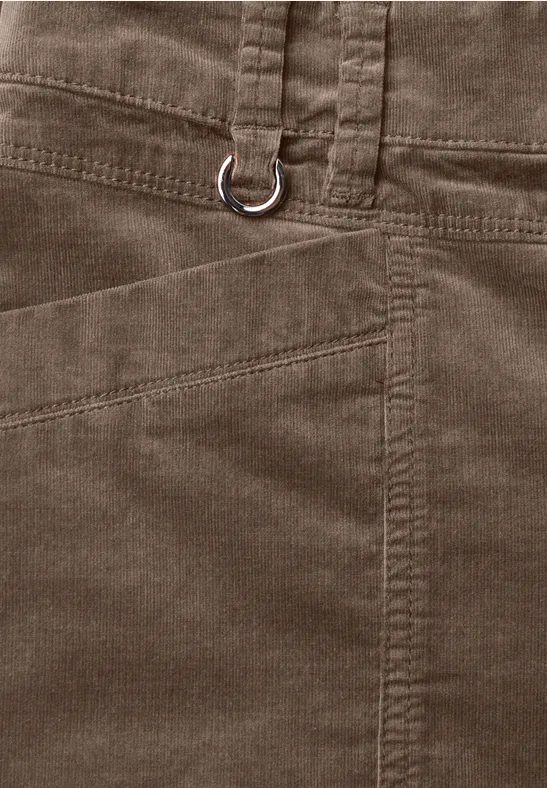 Close-up van een bruine ribfluwelen broek met zijzak en metalen ring aan de riemlus.