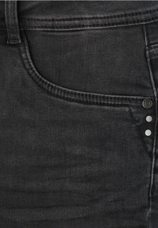 Nahaufnahme einer schwarzen Jeans mit sichtbarer Tasche und Nieten