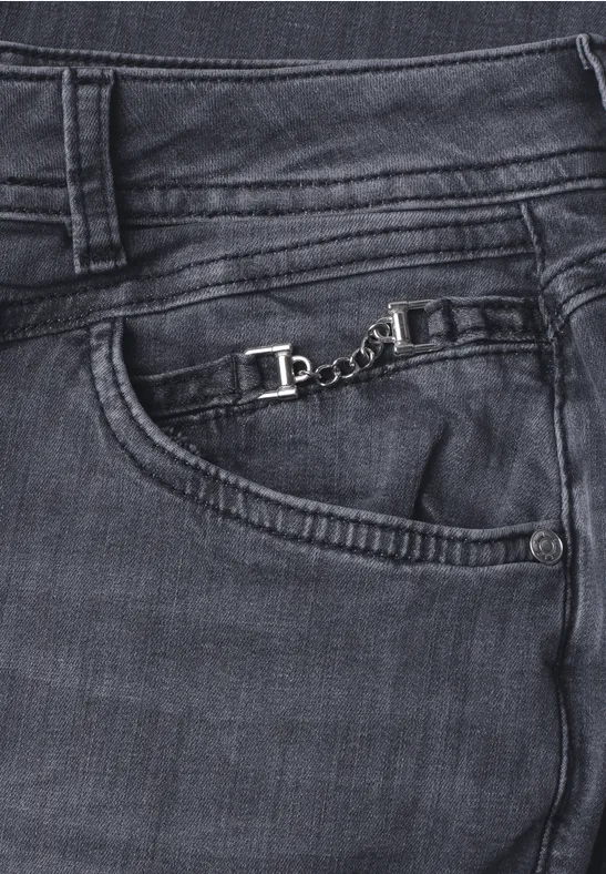 Dunkle Jeans mit sichtbaren Nähten und einer kleinen silbernen Kette an der vorderen Tasche.