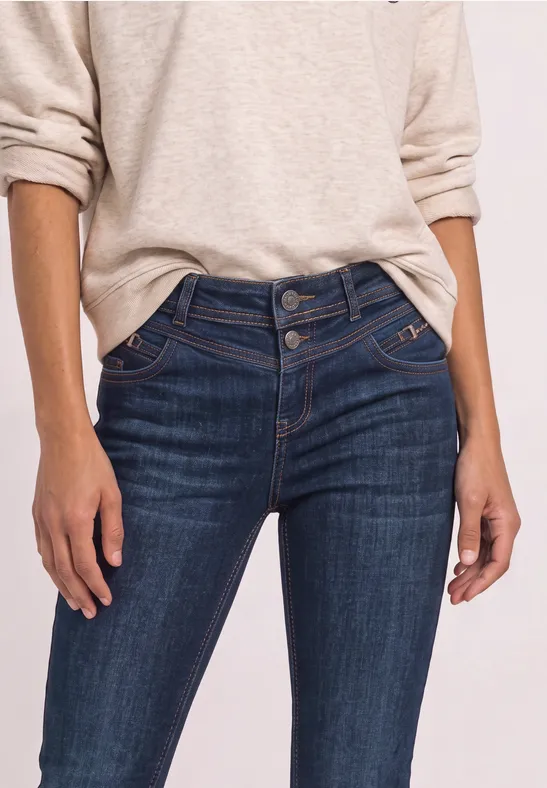 Person trägt dunkelblaue, hochgeschnittene Jeans und helles Langarmshirt.