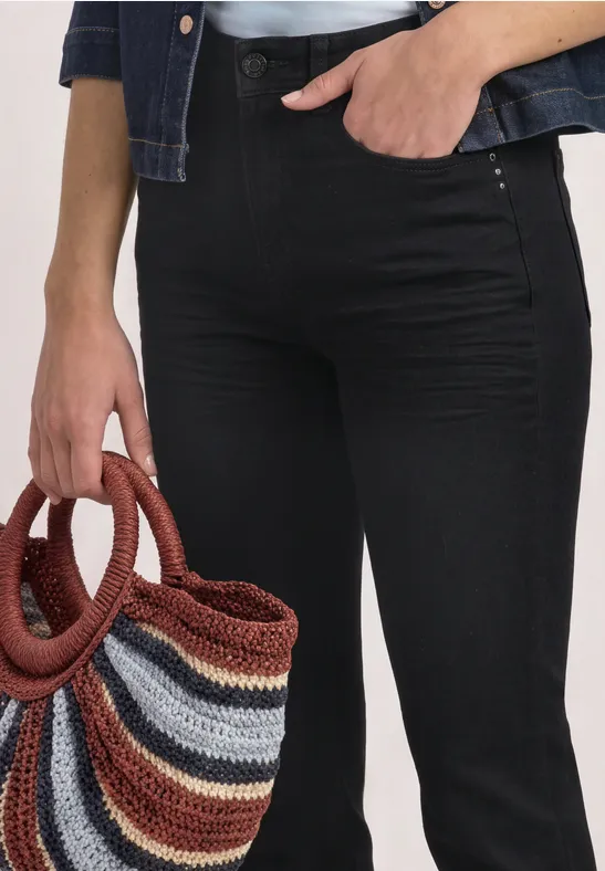 Schwarz gekleidete Person hält gestreiften, mehrfarbigen Strickbeutel an der Hüfte.
