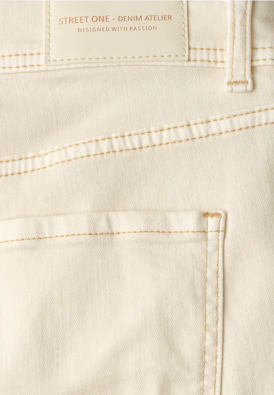 Close-up van achterzijde van een crèmekleurige jeans met zak en sierstiksels