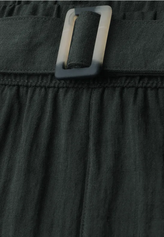 Schwarzer, plissierter Rock mit breitem Gürtel und quadratischer Metallschnalle, Nahaufnahme.