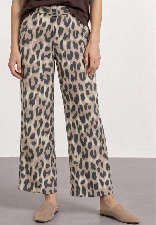 Wijde damesbroek met beige-zwart leopardpatroon, hoge taille, gecombineerd met platte loafers.