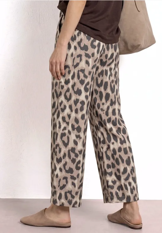 Beige, wijde broek met zwarte luipaardprint, gecombineerd met eenvoudige mocassins.