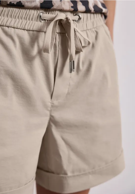 Beige Shorts mit Tunnelzugbund und hochgekrempeltem Saum, kombiniert mit einem Leo-Print-Top.