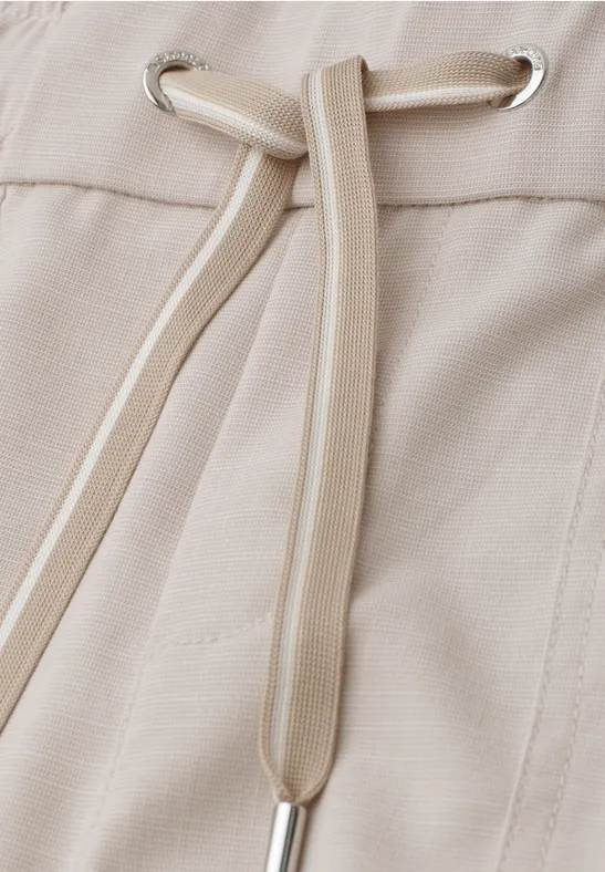 Close-up van een beige stof met een trekkoord door metalen oogjes