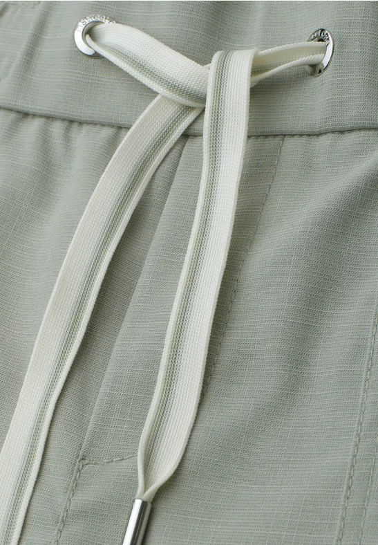 Close-up van lichtgroene broek met witte trekkoord in de taille.