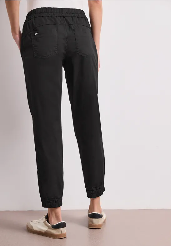 Effen zwarte joggingbroek met elastische taille en aangesnoerde pijpen, achteraan gezien.