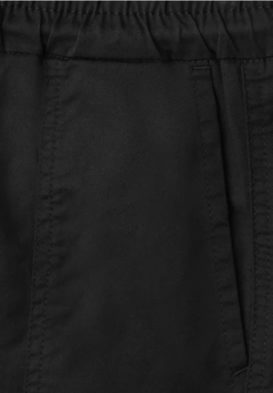 Close-up van een zwarte broek met elastische tailleband en zijzak.