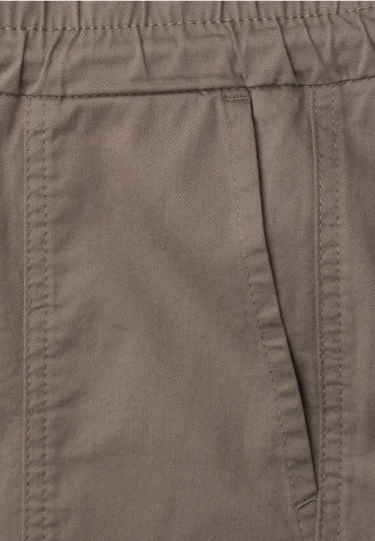 Nahaufnahme einer braunen Hose mit seitlicher Tasche und sichtbaren Nähten.