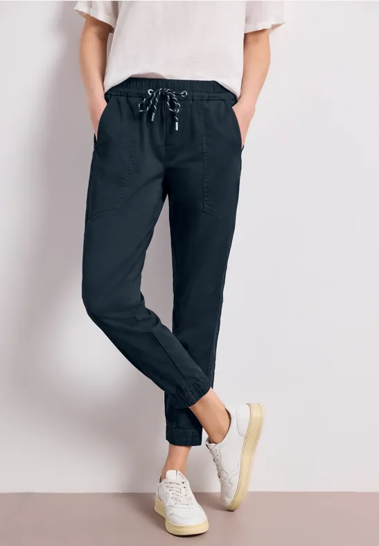 Persoon draagt zwarte jogger met trekkoord en witte sneakers