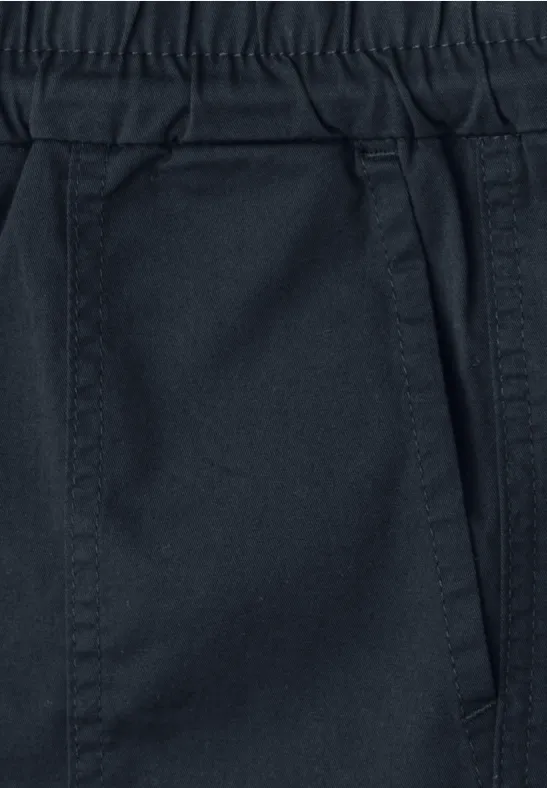 Close-up van een donkerkleurige broek met elastische tailleband en een zijzak.