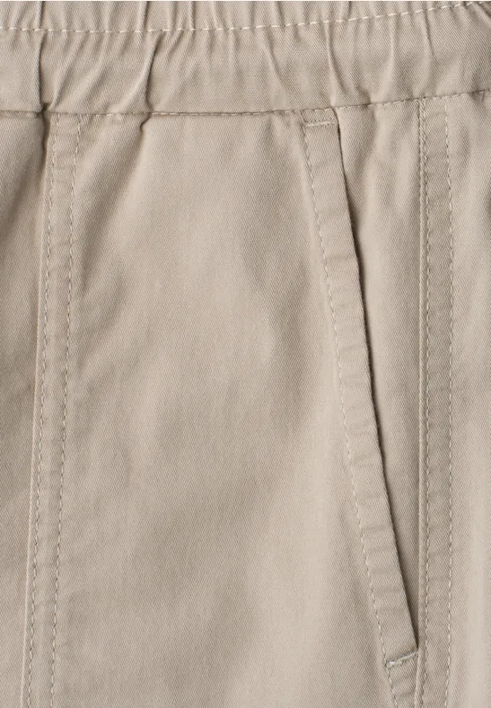 Nahaufnahme einer beigen Hose mit elastischem Bund und seitlicher Tasche