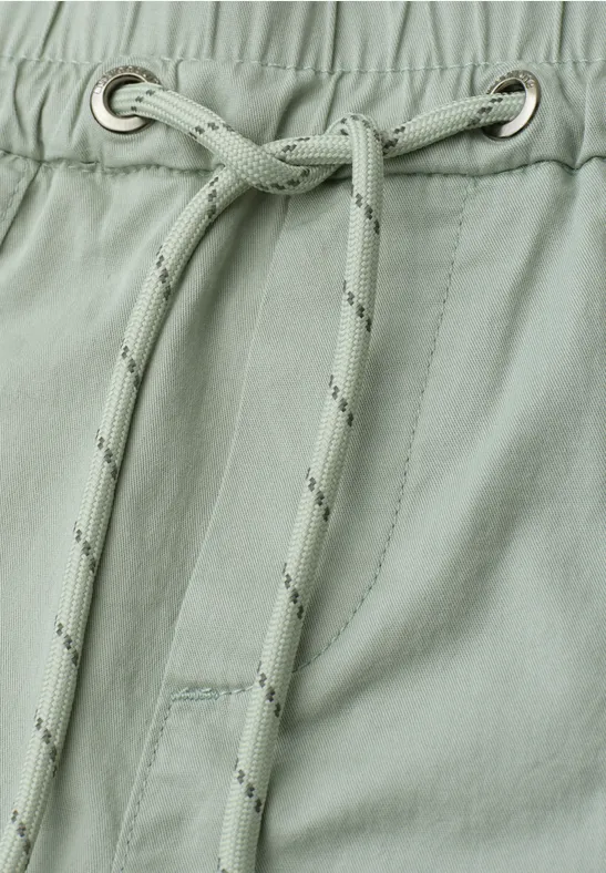 Nahaufnahme eines hellgrünen Kleidungsstücks mit Kordelzug und Metallösen