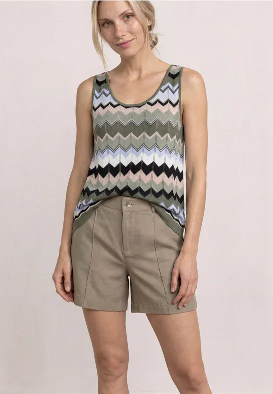 Vrouw draagt een mouwloos zigzagt-shirt en beige short voor lichte achtergrond.