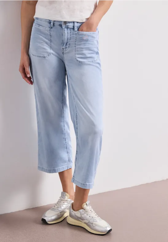 Helle, lässige weite Jeans in Cropped-Länge kombiniert mit silbernen Sneakern.