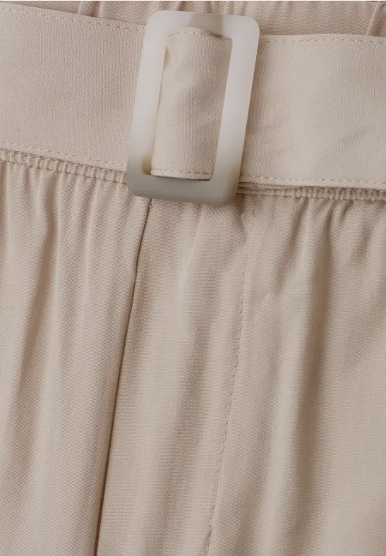 Nahaufnahme eines beigen Stoffbunds mit rechteckiger Schnalle an einer Hose