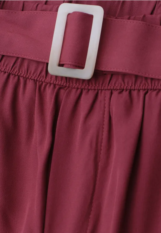 Nahaufnahme eines burgunderroten Kleidungsstücks mit elastischem Bund und weißer Schnalle.