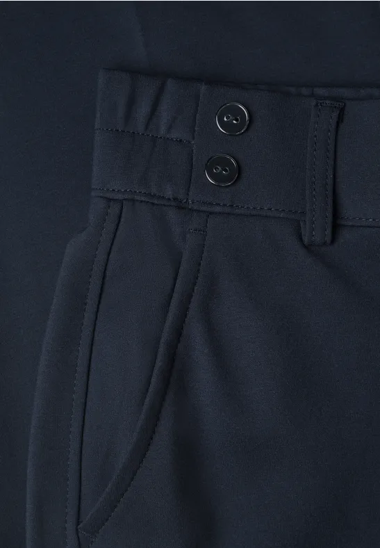 Nahaufnahme einer dunkelblauen Hose mit zwei Knöpfen, Gürtelschlaufen und seitlicher Tasche.