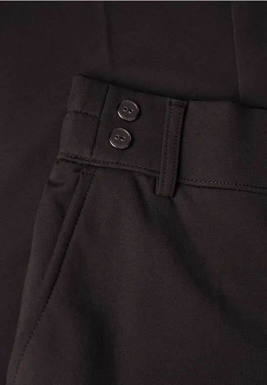 Nahaufnahme einer schwarzen Hose mit Gürtelschlaufen, zwei Bundknöpfen und seitlicher Tasche
