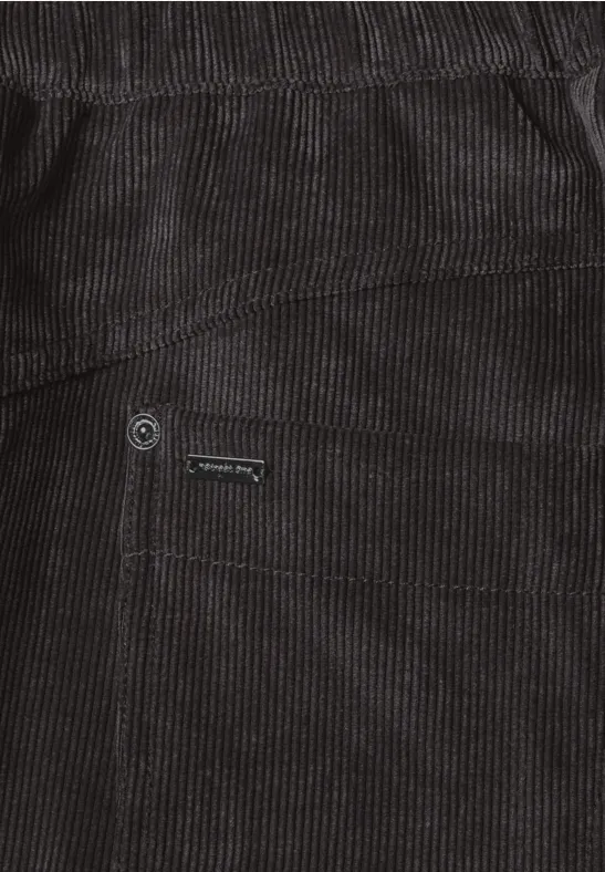 Detailaufnahme einer schwarzen Cordhose mit Taschennaht und Metallknopf