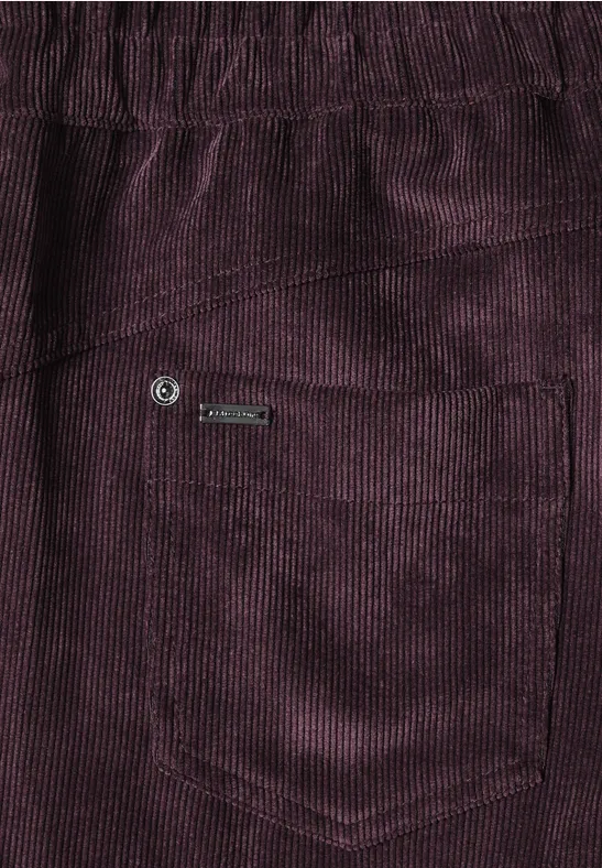 Nahaufnahme einer violetten Cordhose mit Tasche und Logo-Label.