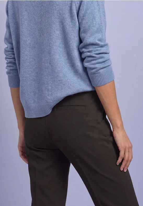 Rückenansicht einer Person in blauem Pullover und dunkler Hose.
