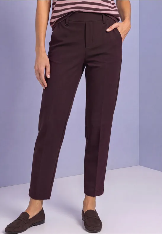 Dunkelbraune, knöchellange Stoffhose mit geradem Schnitt und Loafers.