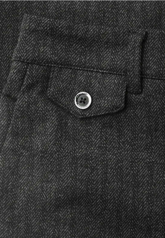 Gros plan d’un pantalon gris foncé en chevrons avec petite poche à rabat et bouton.