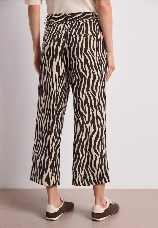 Rückansicht einer Person, die weite, zebragemusterte Hosen und braune Mokassins trägt.