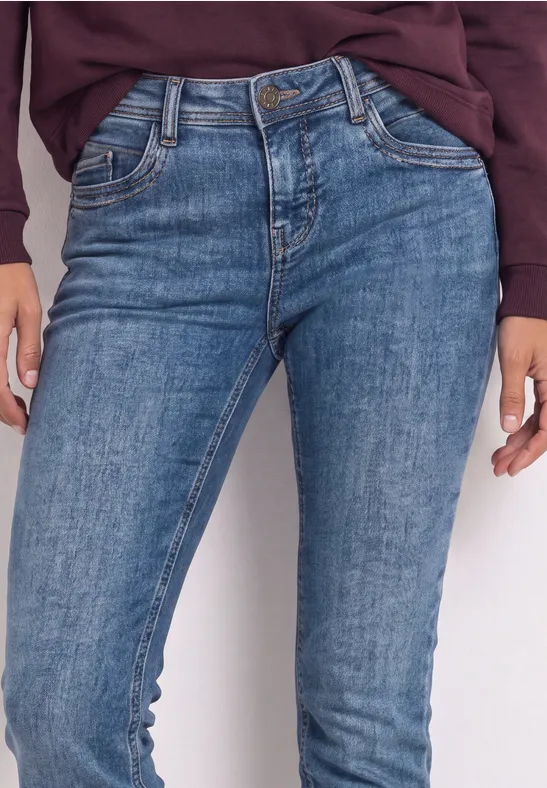 Nahaufnahme einer Person in blauen Jeans und lockerem Oberteil.