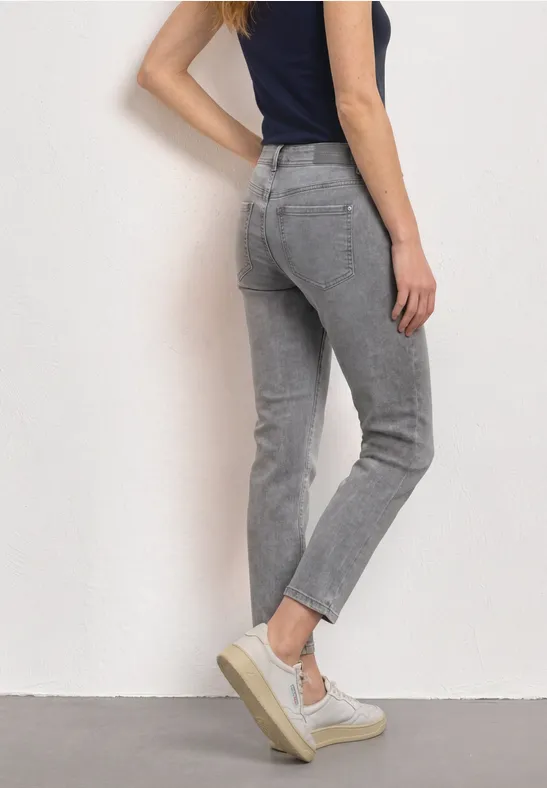 Eine Frau trägt eine stilvolle graue Jeans und weiße Plateausneaker.