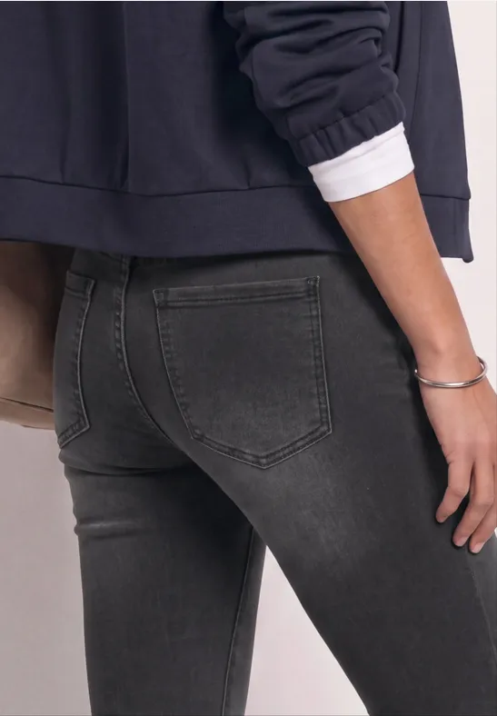 Person von hinten in dunkelgrauen Skinny-Jeans und dunkelblauem Oberteil.