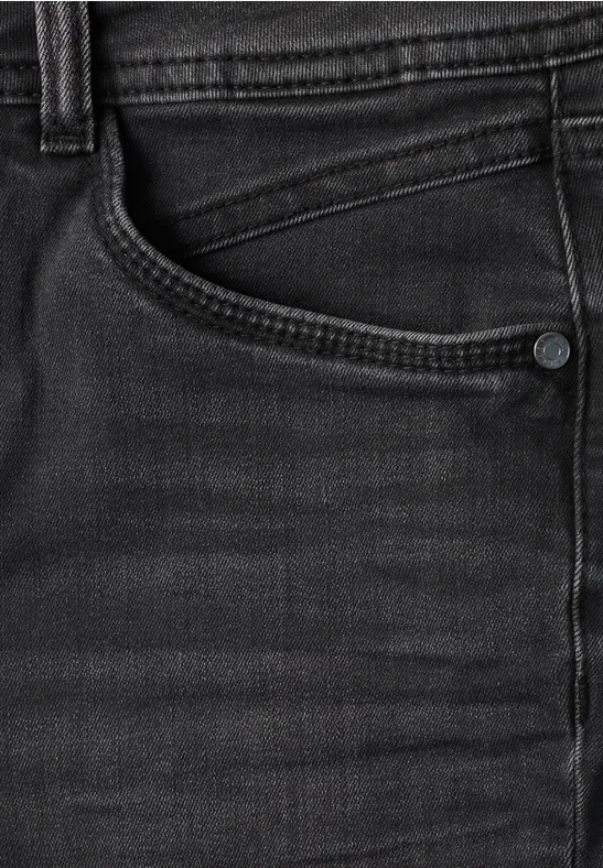 Nahaufnahme einer schwarzen Jeanshose mit sichtbarer Tasche und Nahtdetails.