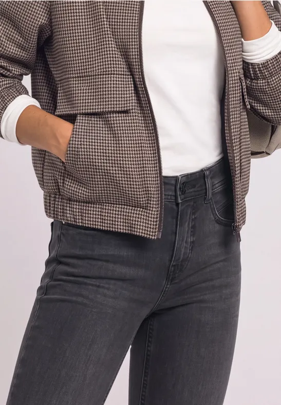 Oberkörper einer Person mit karierter Jacke, weißem Shirt und dunklen Jeans.