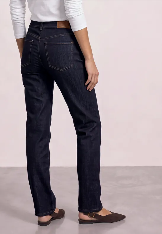 Person von hinten mit dunkelblauen geraden Jeans und braunen Ballerinas.