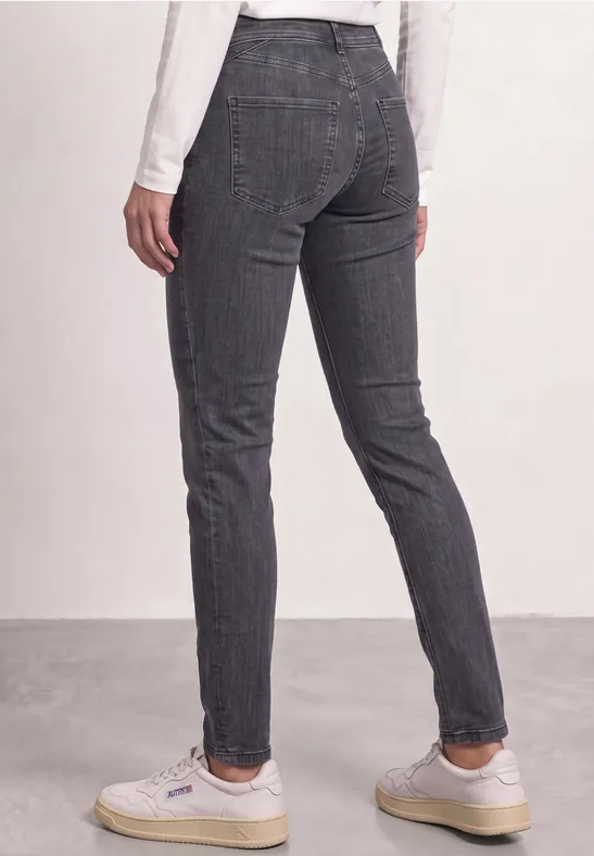 Rückansicht einer Person, die dunkelgraue, karierte Slim-Hose und weiße Sneaker trägt.