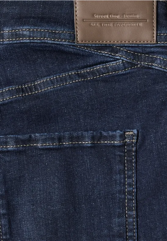 Close-up van een donkerblauwe spijkerbroek met opvallende stiksels en een bruin lederen label in de taille