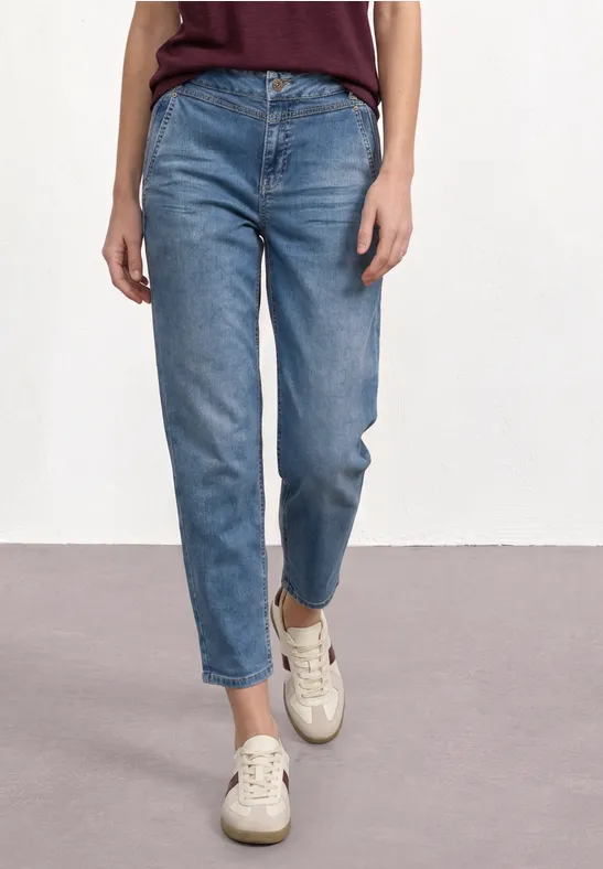 Jeans met mid-rise en rechte pijpen, gecombineerd met beige sneakers.