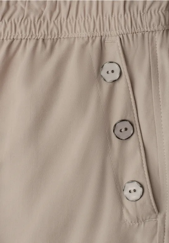 Beige broek met elastische taille en drie knopen aan de zijkant.
