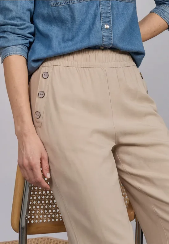 Damessbroek in beige met knoopdetail aan de zijkant, gecombineerd met een denimblouse.
